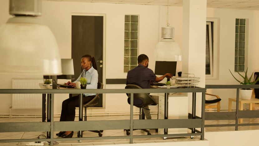male-employee-leaving-office-job-waving-colleague-woman-sitting-desk-working-business-report-presentation-doing-executive-project-work-company-network-sunset-830x467% | AI Consultancy Tanzania | ITEXPERT-LAPTOPEXPERT